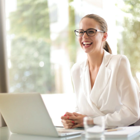 a woman in glasses sitting at a table with a laptop