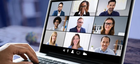 a person using a laptop with a video conference on the screen