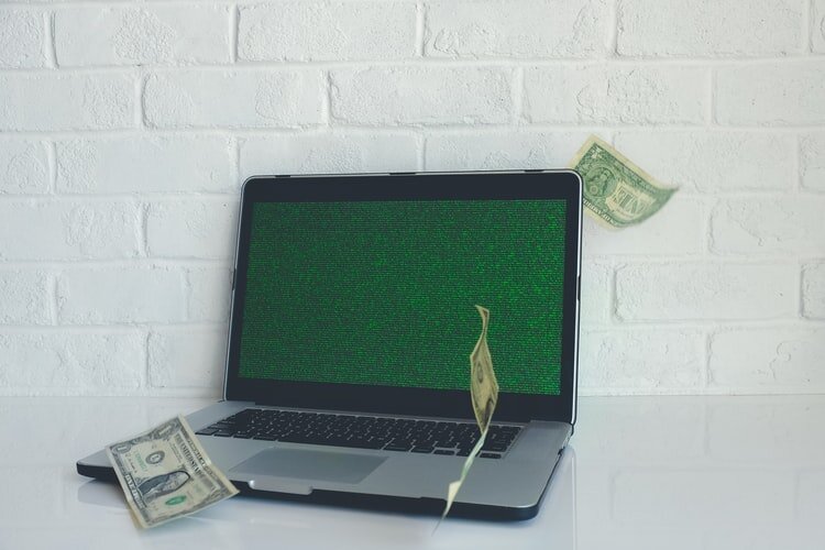 a laptop with money on top of it