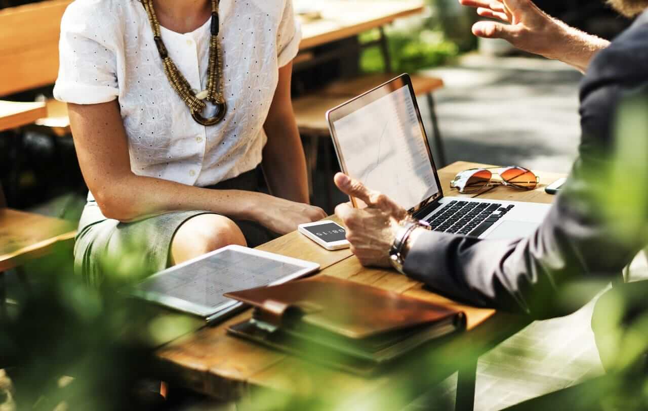 two people sitting at a table with a laptop.
