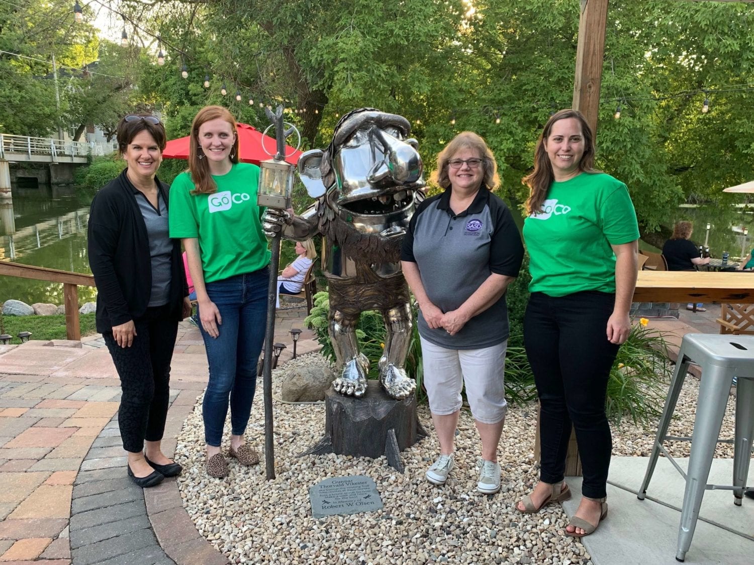 three women standing next to a statue of a dog