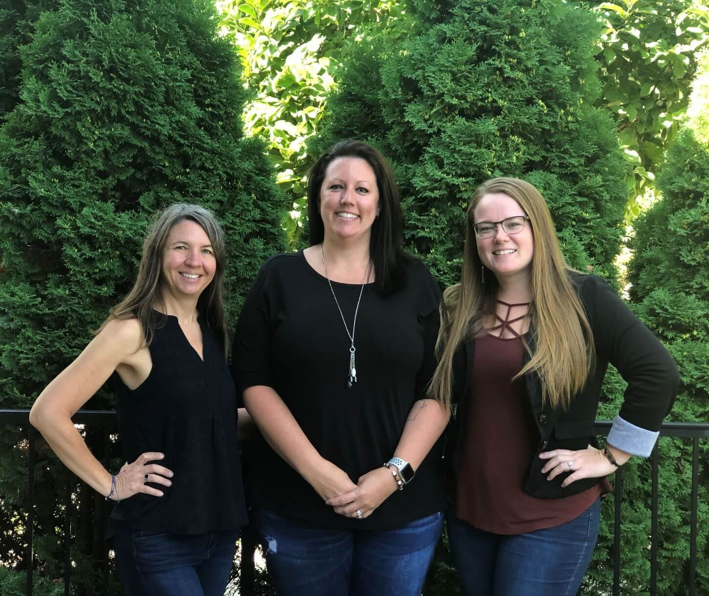 three women standing in front of a tree