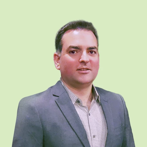 a man in a suit and tie standing in front of a green background