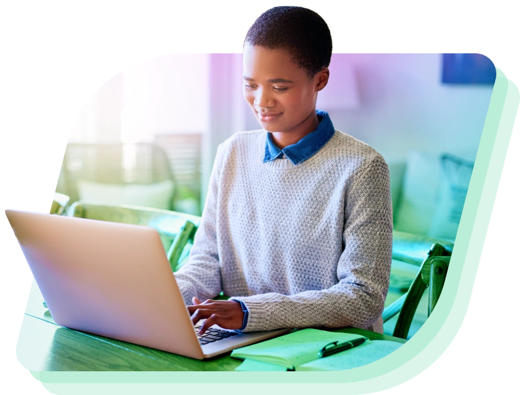 a boy sitting at a table using a laptop