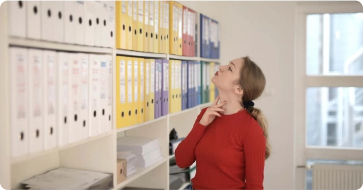 a woman is standing in front of a wall full of files