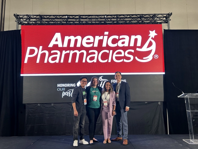 two people standing on a stage with an american pharmacy sign
