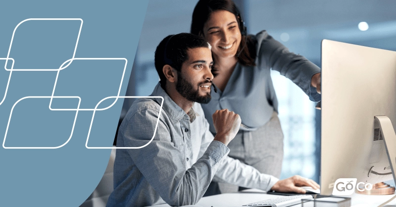 Two people in business attire look at a computer monitor.