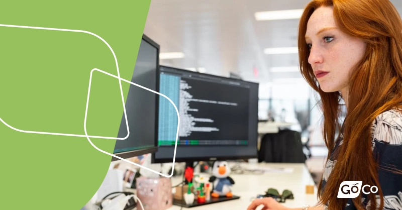 A woman sitting at a desk examines data on a computer monitor