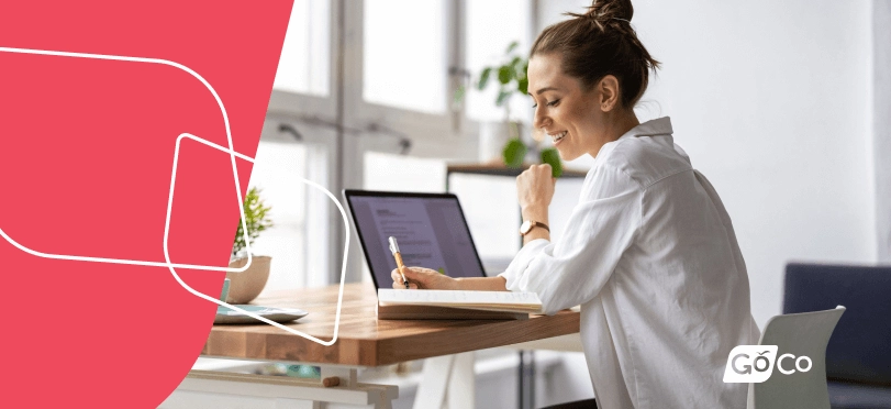 A woman seated at a desk, working at a laptop.