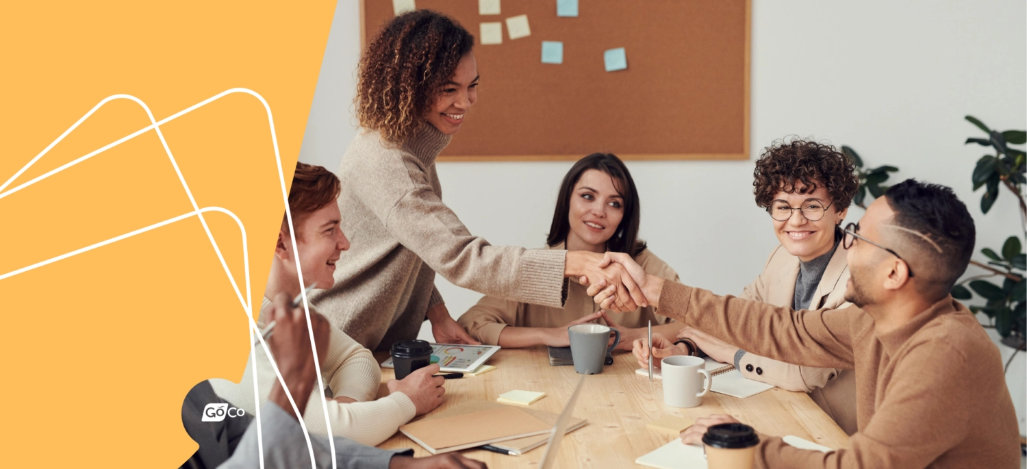 a group of people sitting around a table with a laptop