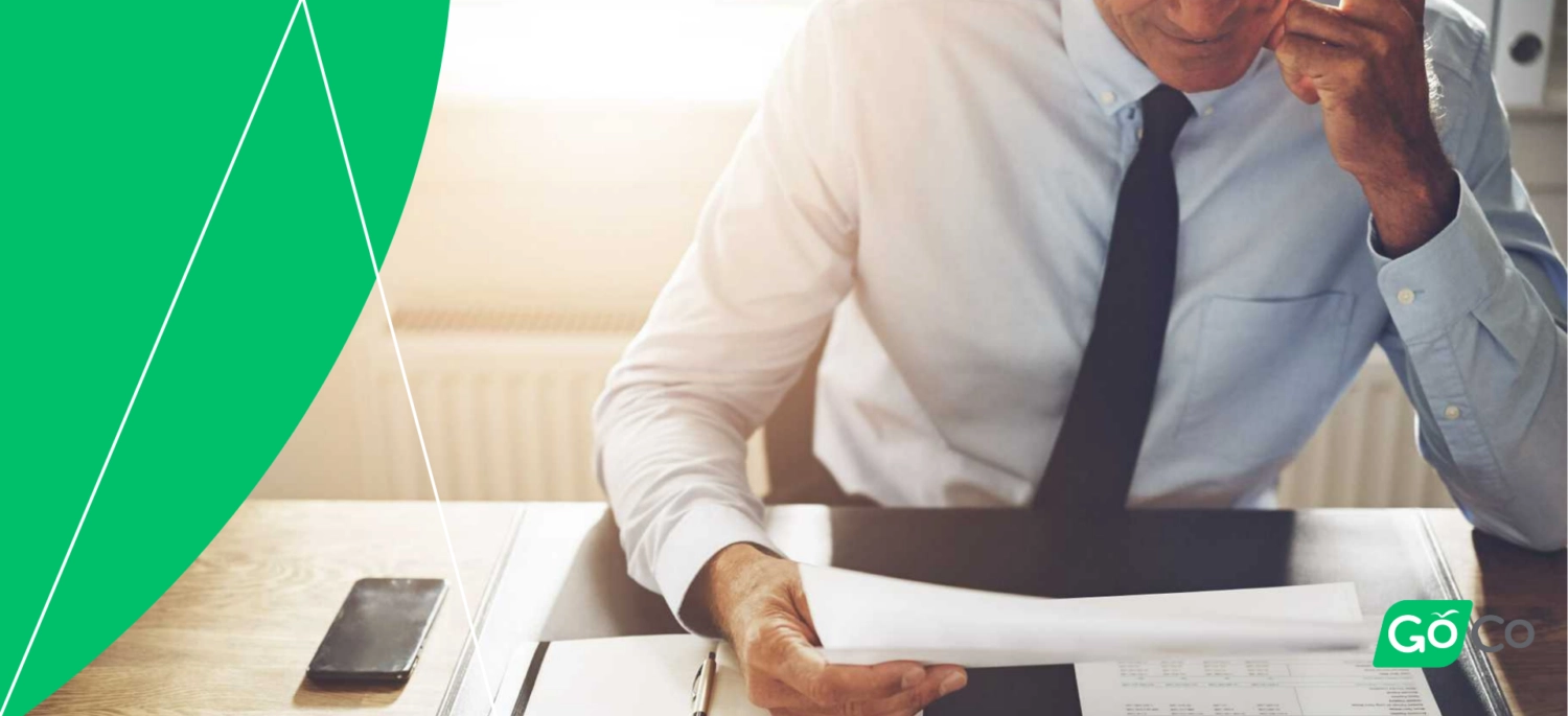 A man in business attire, sitting at a desk and look at a form.