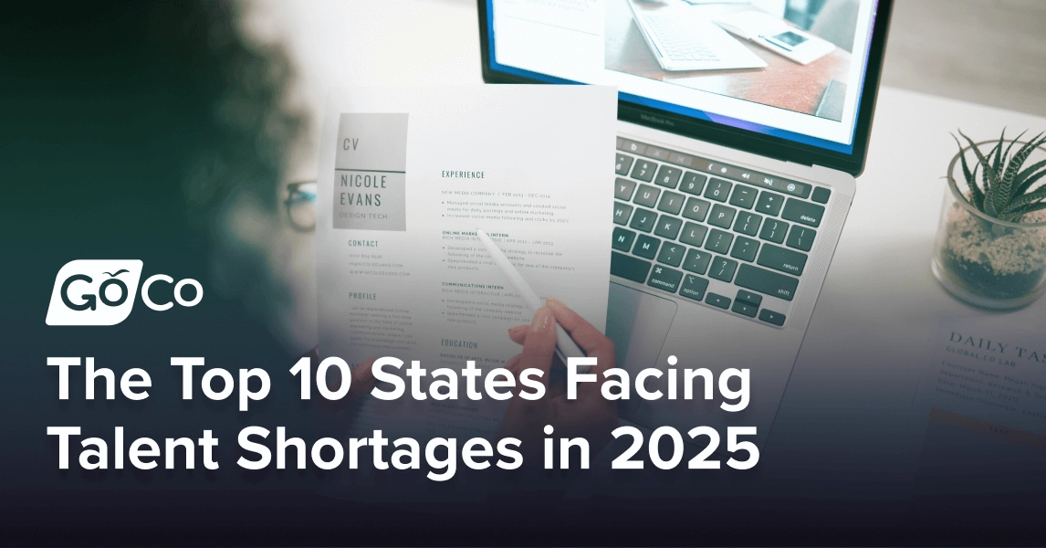 A woman seated at a desk looks over a resume.