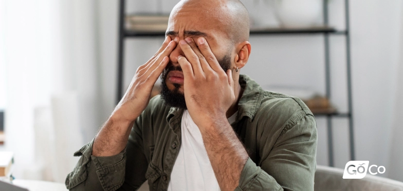 a man with a headache sitting on a couch
