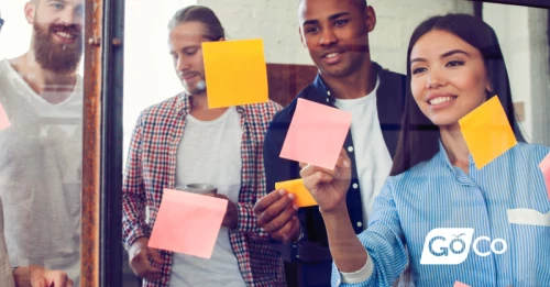 group of people holding sticky notes in front of a mirror
