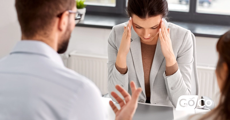 a woman sitting at a desk with her head in her hands