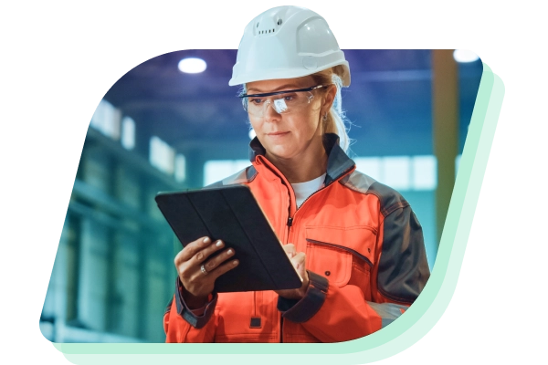 a woman in a hard hat and safety vest holding a tablet